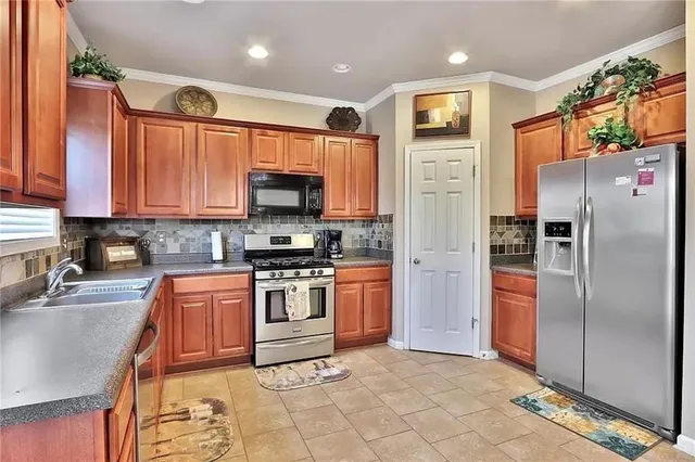 a kitchen with stainless steel appliances granite countertop a refrigerator a stove a sink and a microwave