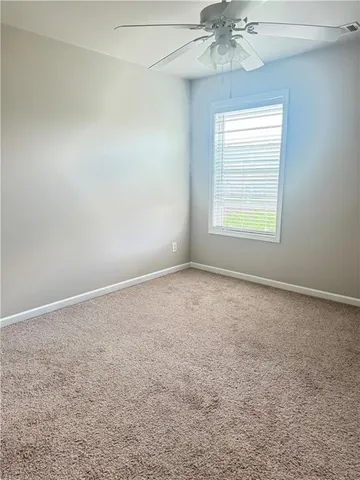 an empty room with a chandelier fan and windows
