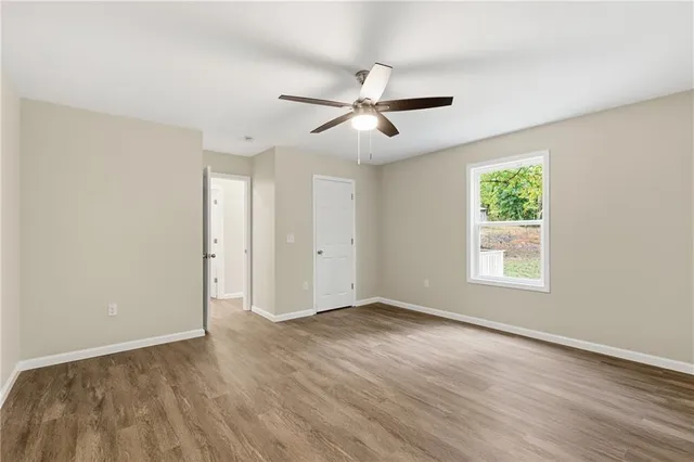a view of empty room with wooden floor and fan