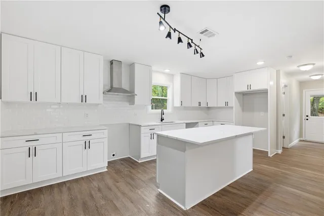 a kitchen with kitchen island a sink and white cabinets