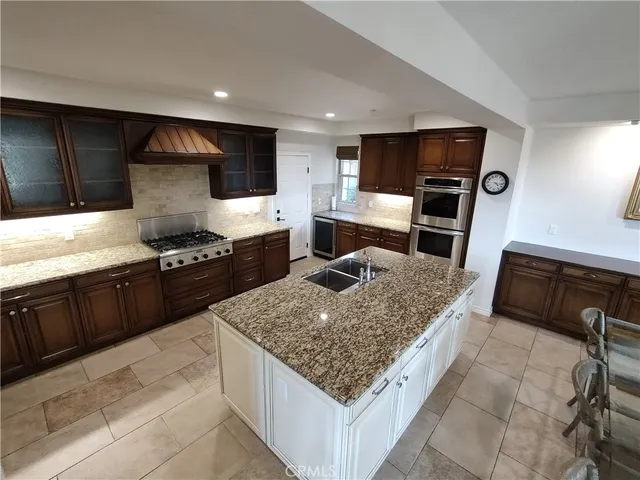 a kitchen with stainless steel appliances granite countertop a stove top oven a sink and a refrigerator