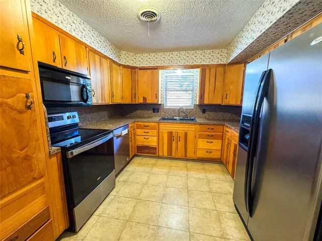 a kitchen with stainless steel appliances granite countertop a refrigerator and a sink