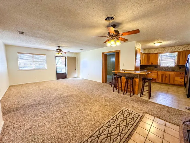 a view of an empty room and kitchen with wooden floor