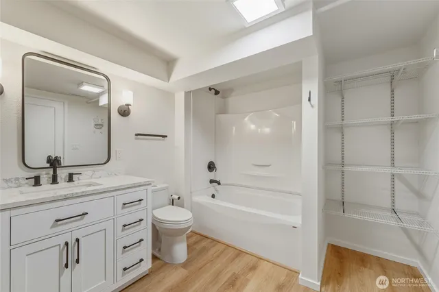 a bathroom with a bathtub shower sink vanity mirror and toilet