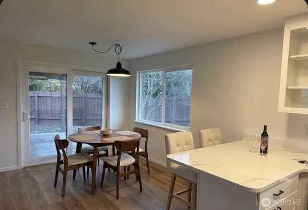 a open kitchen with kitchen island a stove a sink a refrigerator and white cabinets with wooden floor
