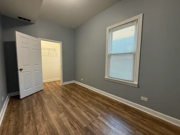 an empty room with wooden floor closet and windows