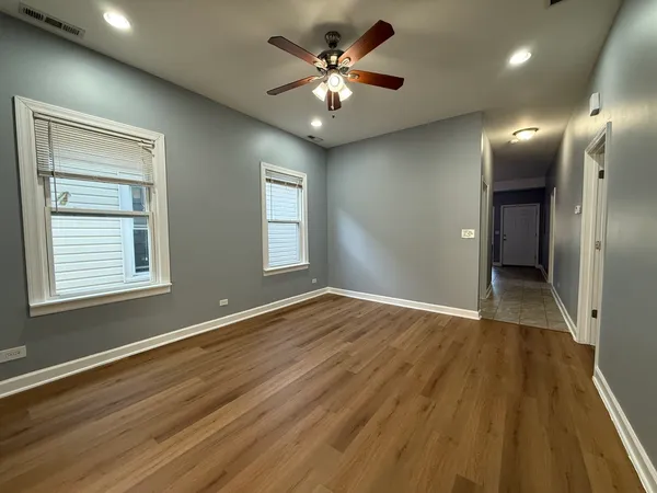 a view of an empty room with window and wooden floor