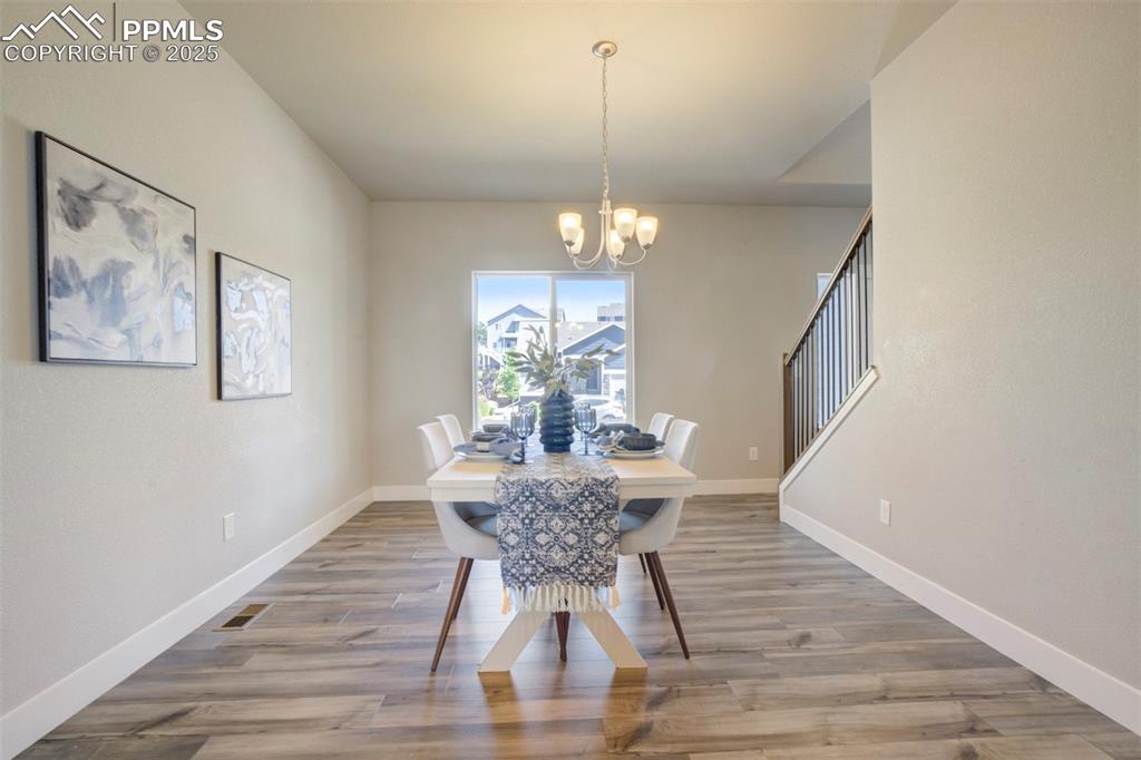 5633 Makalu Drive Colorado Springs, CO 80924 - Photo 14 of 48 a dining room with wooden floor a chandelier a wooden table and chairs
