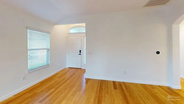 a view of empty room with wooden floor and fan