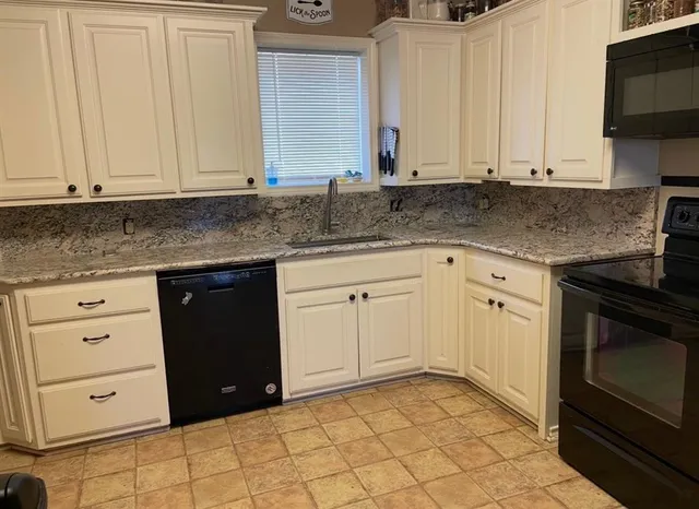 a kitchen with granite countertop white cabinets and stainless steel appliances