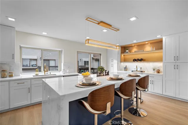 a kitchen with a sink a stove a kitchen island with chairs and wooden floor