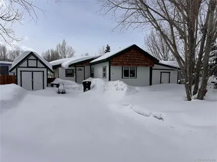 a view of a house with large trees covered in snow