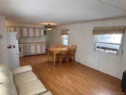 a living room with furniture and a dining table with wooden floor