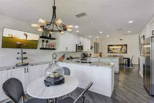 a kitchen with stainless steel appliances kitchen island granite countertop a sink a stove a dining table and chairs