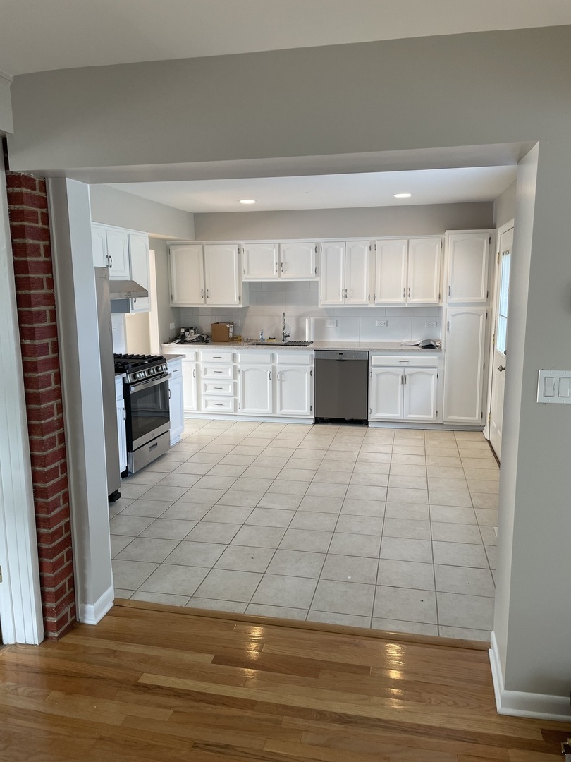 1087 Leahy Circle Des Plaines, IL 60016 - Photo 2 of 9 a large white kitchen with kitchen island a stove a sink and a refrigerator
