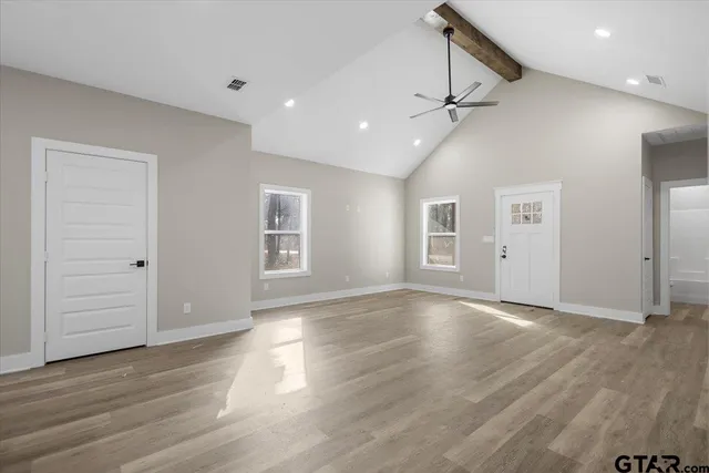 an empty room with wooden floor cabinet and windows
