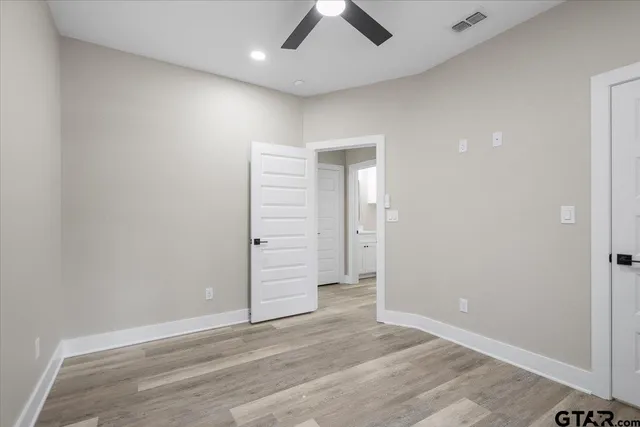 an empty room with wooden floor and ceiling fan