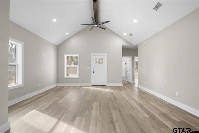 an empty room with wooden floor and windows