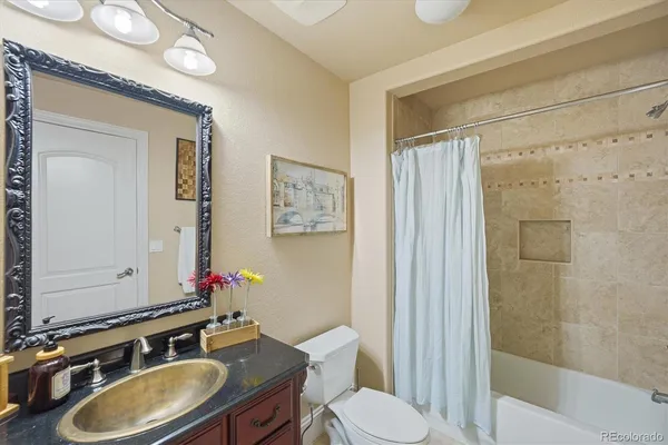 a bathroom with a granite countertop sink toilet a mirror and shower