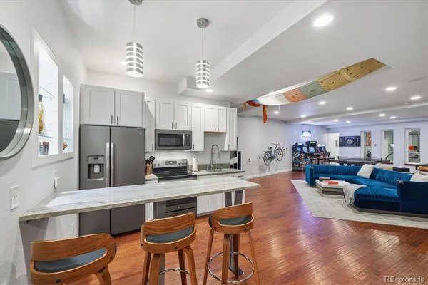 a kitchen with stainless steel appliances kitchen island granite countertop a refrigerator a stove a sink dishwasher and a dining table with wooden floor