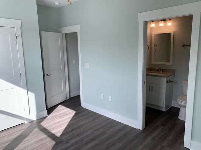 a view of a hallway with wooden floor and a bathroom