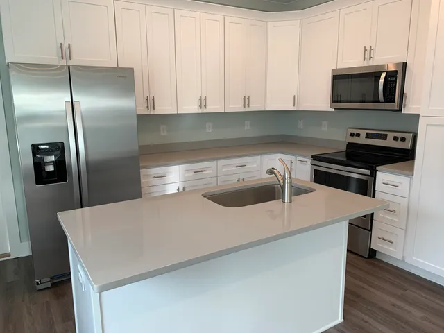a kitchen with stainless steel appliances a microwave a sink a stove and white cabinets