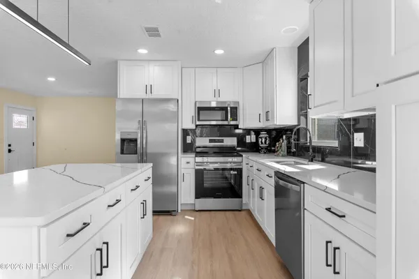 a kitchen with kitchen island white cabinets appliances and sink