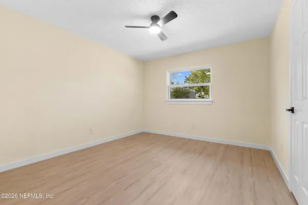 an empty room with wooden floor ceiling fan and windows