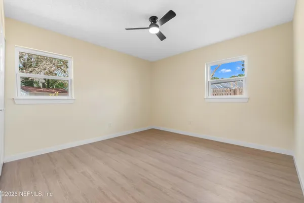 an empty room with a window and a ceiling fan