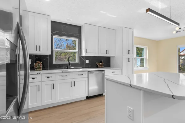 a kitchen with stainless steel appliances granite countertop a stove a sink and white cabinets