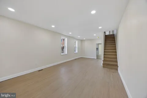 an empty room with wooden floor and white stairs