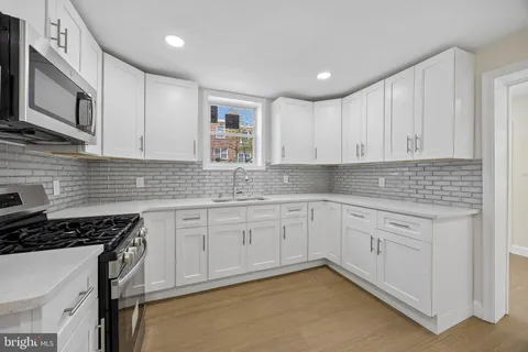 a kitchen with granite countertop white cabinets stainless steel appliances and a sink