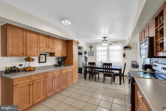 a large kitchen with cabinets chairs and refrigerator