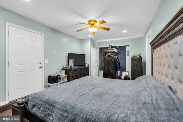 a living room with furniture a flat screen tv and a ceiling fan