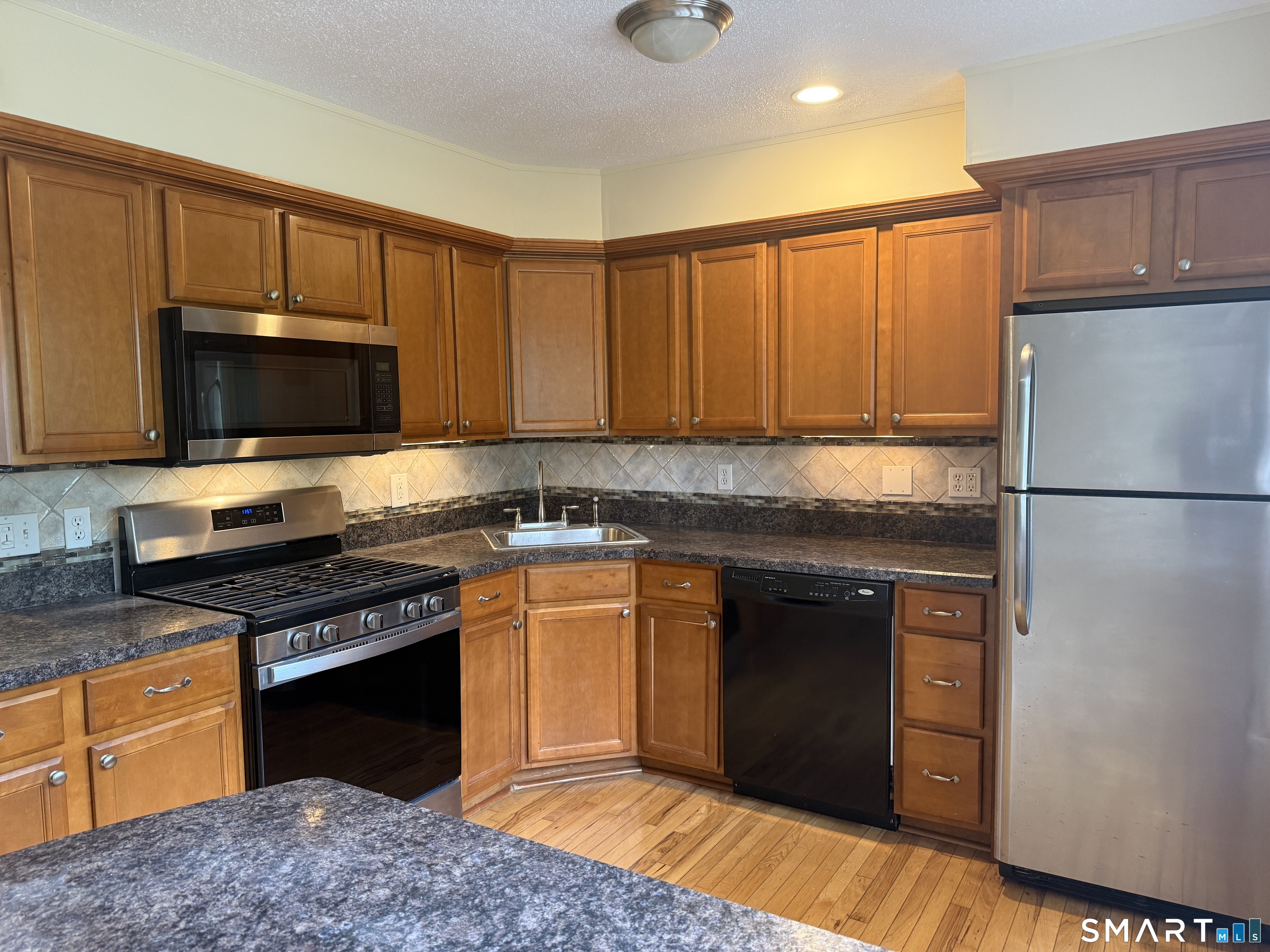 116 Commerce Street, Unit 5 Clinton, CT 06413 - Photo 7 of 18 a kitchen with stainless steel appliances granite countertop a stove top oven a sink dishwasher and a refrigerator with wooden cabinets