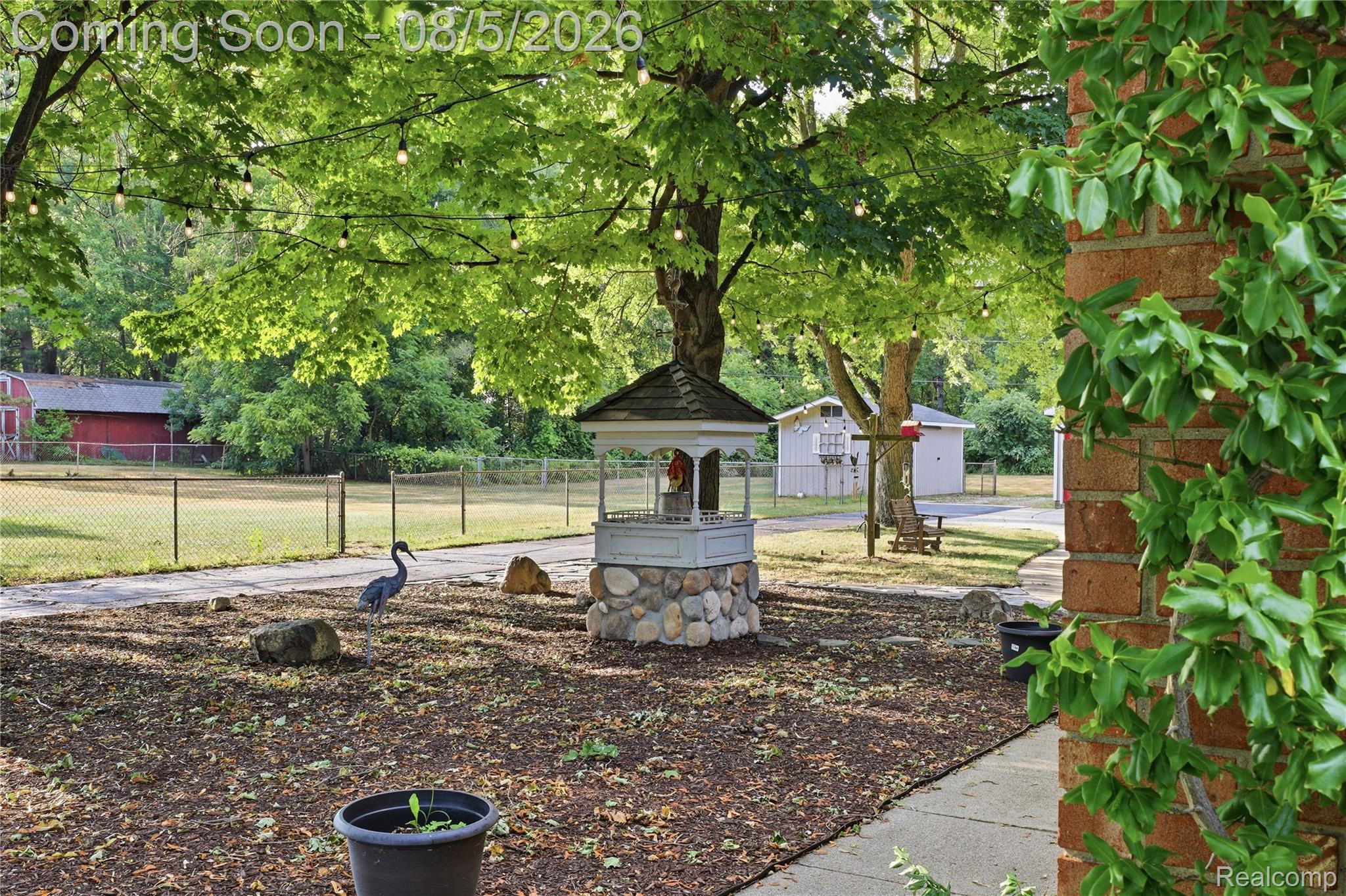 6478 West Stanley Road Mount Morris, MI 48458 - Photo 10 of 80 Expansive outdoor area featuring mature trees, string lights, and a decorative wishing well with a stone base