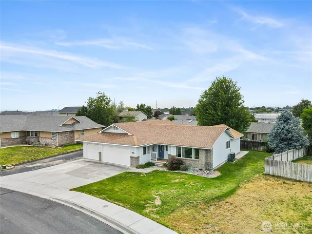 an aerial view of residential houses with yard and car parked