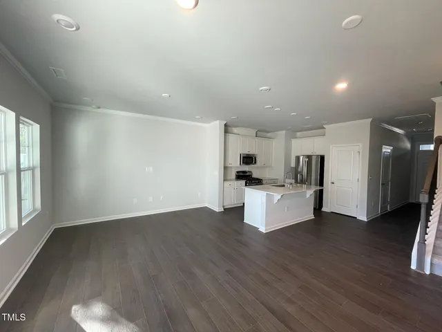 a view of kitchen with stainless steel appliances kitchen island wooden floors and living room view