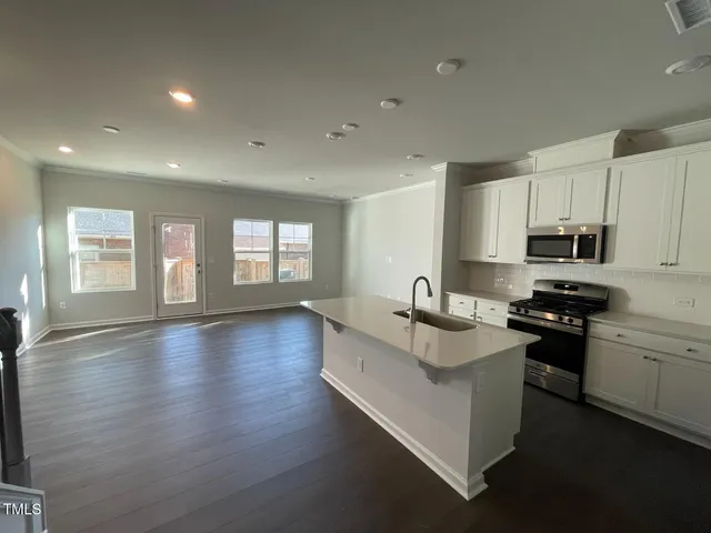 a kitchen with stainless steel appliances granite countertop a sink dishwasher stove and white cabinets with wooden floor