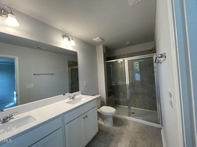 a bathroom with a double vanity sink toilet and shower