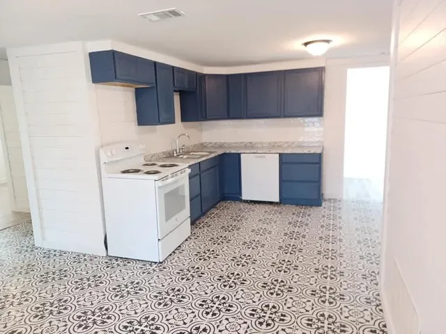a kitchen with granite countertop a stove a sink and a refrigerator