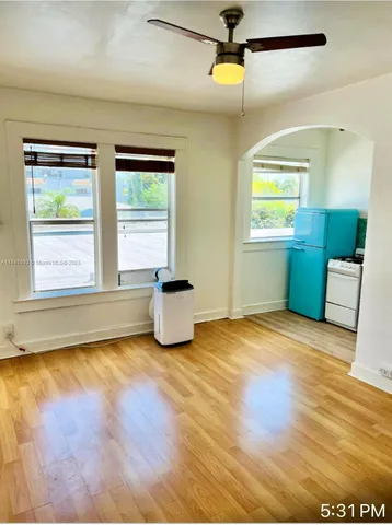 a view of an empty room with a window and wooden floor