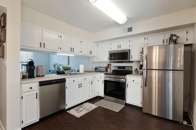 a kitchen with stainless steel appliances granite countertop a refrigerator stove a sink and dishwasher with wooden floor