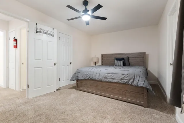 a bedroom with a large bed and a chandelier fan