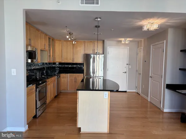 a kitchen with stainless steel appliances granite countertop a refrigerator a sink a stove and oven with wooden floor