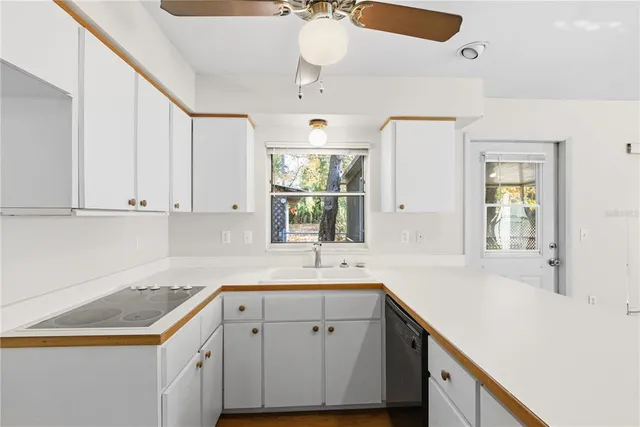 a kitchen with a sink dishwasher and white cabinets with wooden floor
