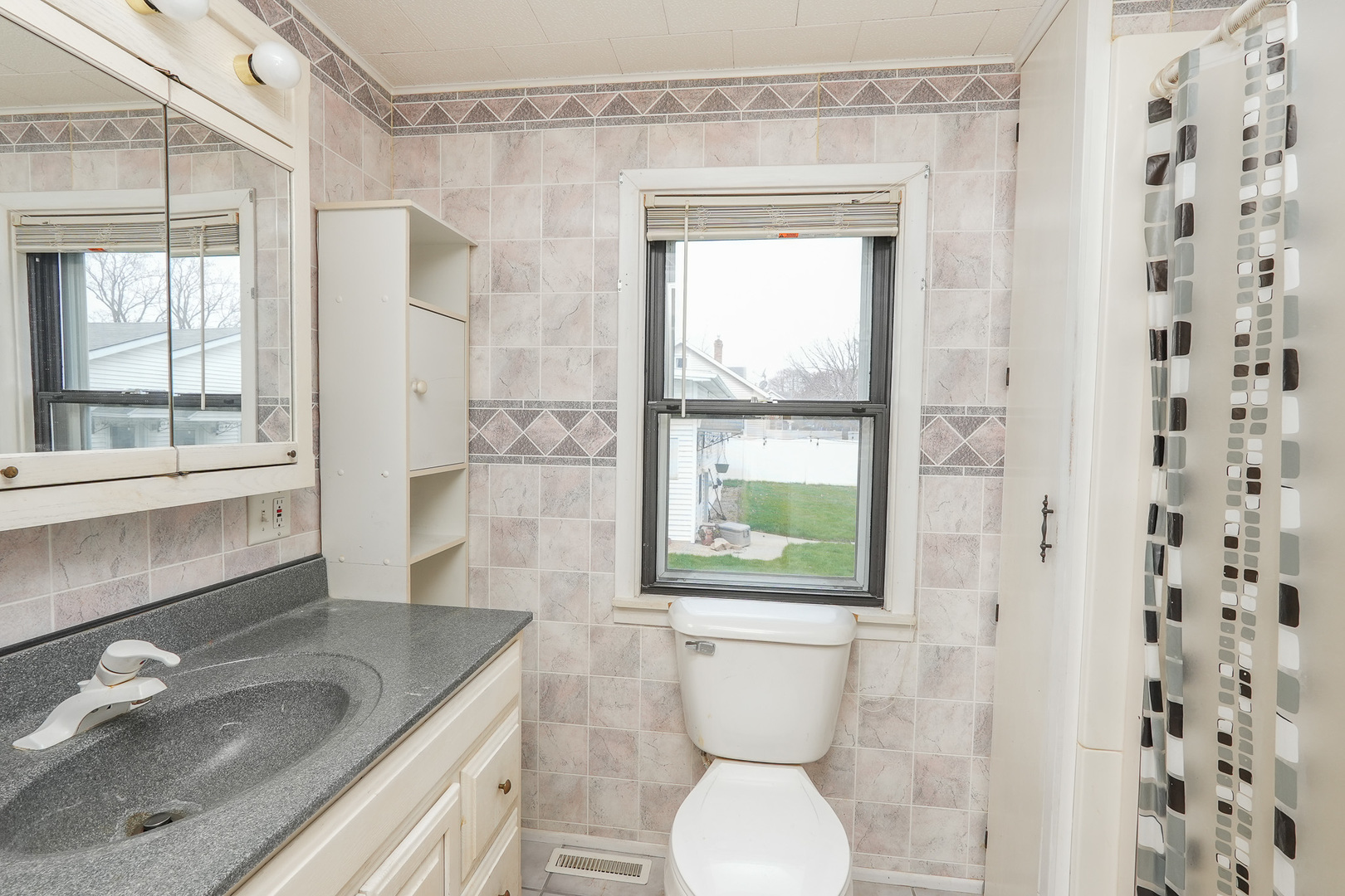 141 West 1st Street Manteno, IL 60950 - Photo 9 of 16 a bathroom with a granite countertop sink a toilet a window and shower