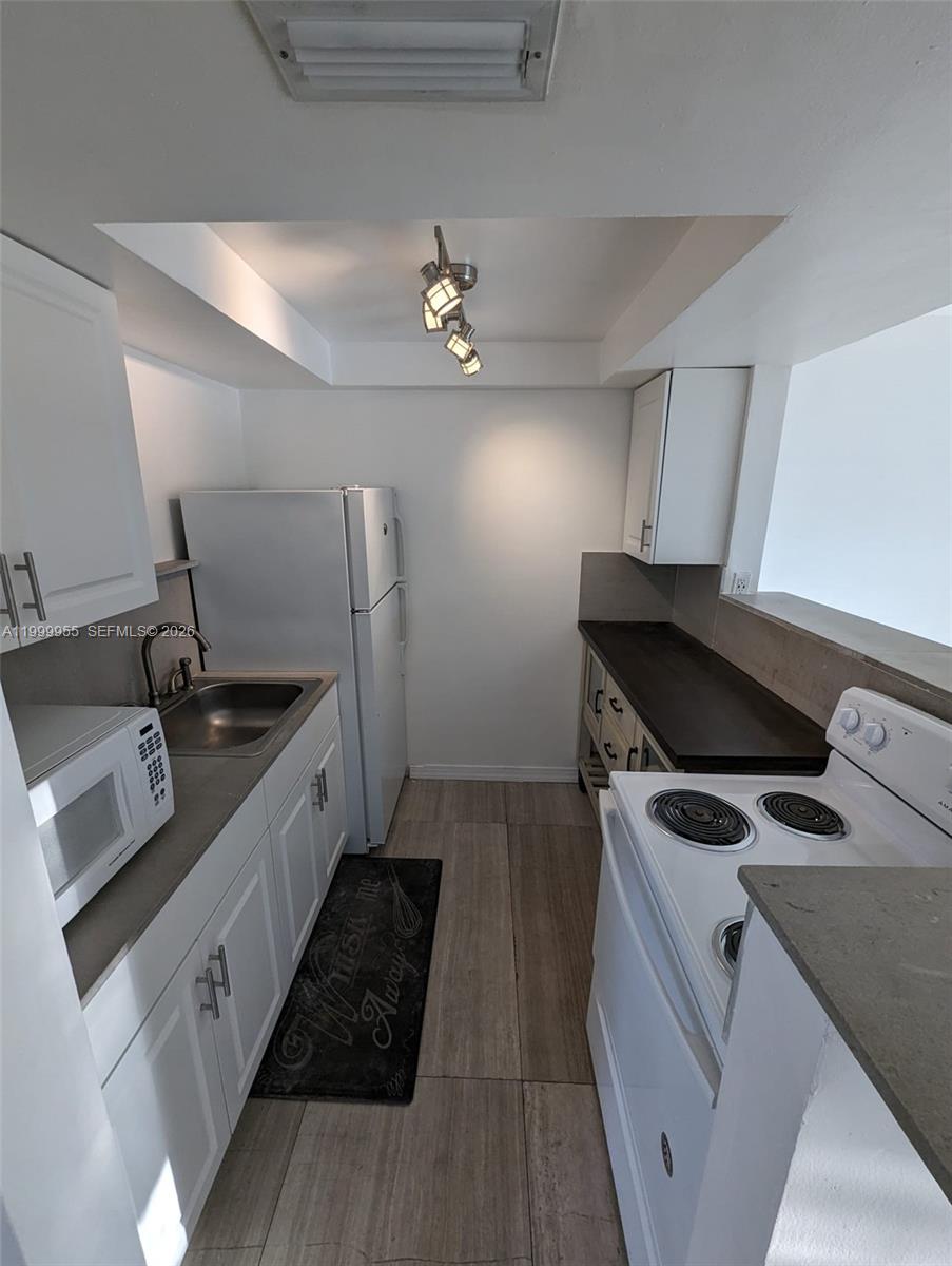 7360 Southwest 82nd Street, Unit E202 Miami, FL 33143 - Photo 4 of 11 a kitchen that has a sink and a stove in it
