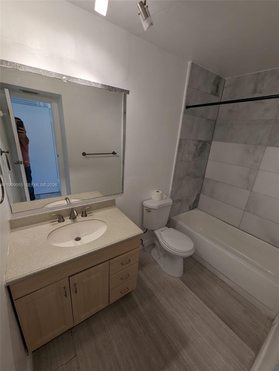 7360 Southwest 82nd Street, Unit E202 Miami, FL 33143 - Photo 8 of 11 a bathroom with a toilet sink and mirror
