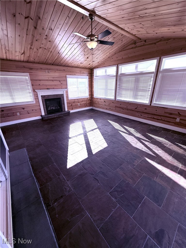 5115 Raspberry Lane Mineral Ridge, OH 44440 - Photo 14 of 25 Unfurnished living room with wooden walls, a fireplace with raised hearth, ceiling fan, lofted ceiling, and wooden ceiling